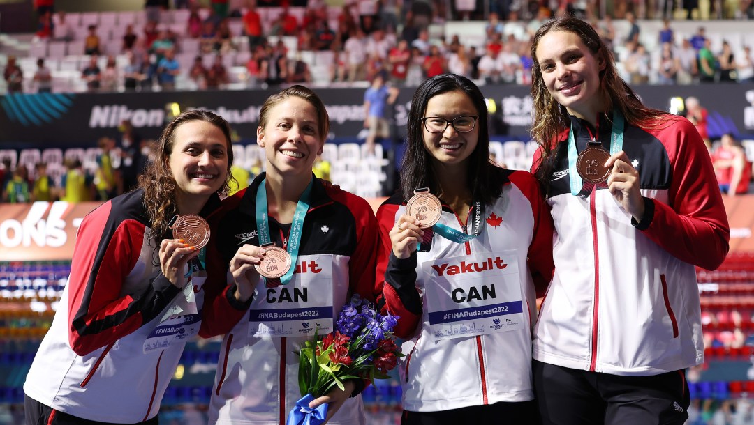 Four swimmers pose with bronze medals