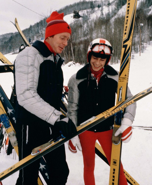 Steve Collins receives instruction from a coach while holding his skis 