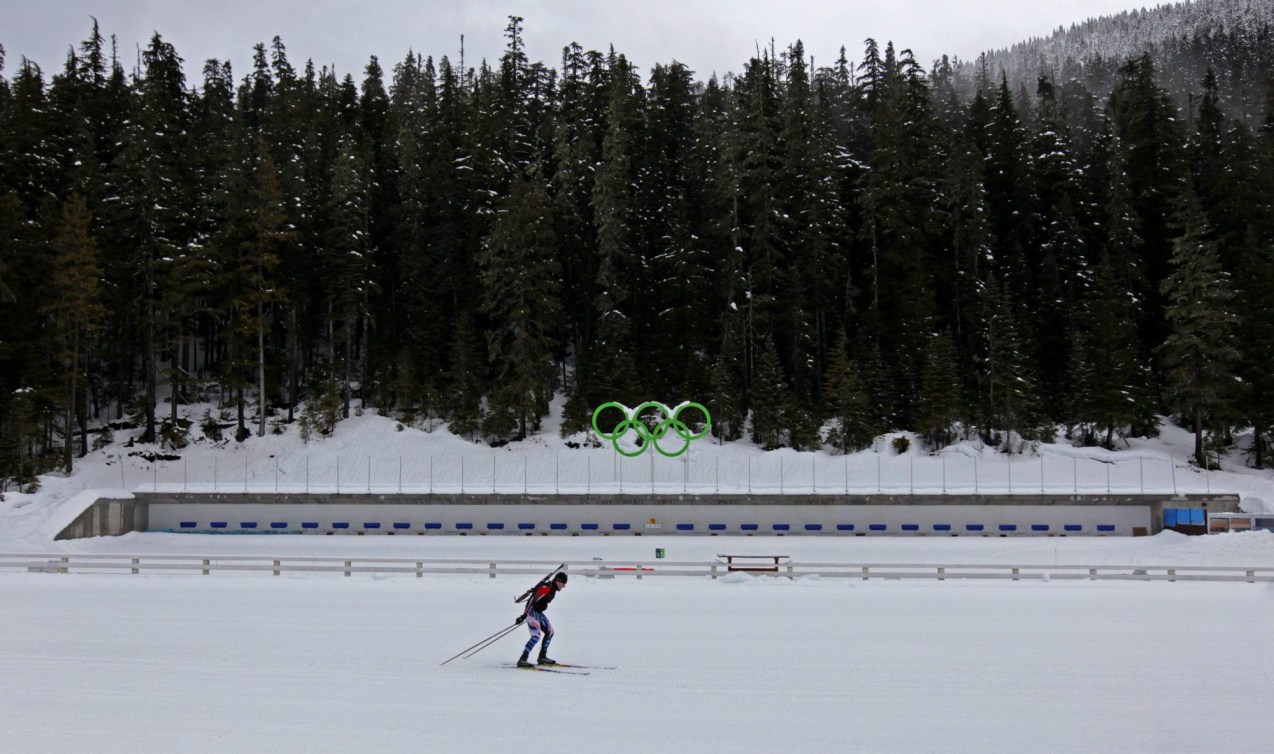 Wide scenic of one skier in front of a biathlon shooting range