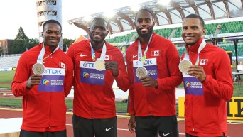 Men's relay team members hold their gold medals
