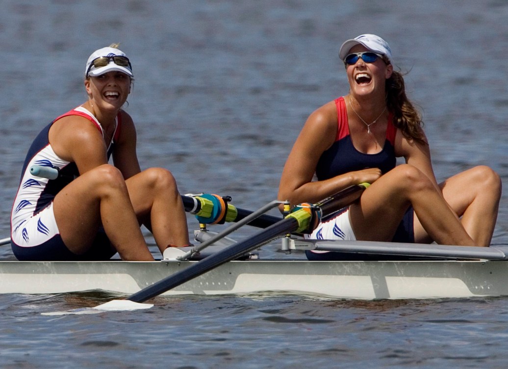 Two female rowers laugh in their boat at the end of a race