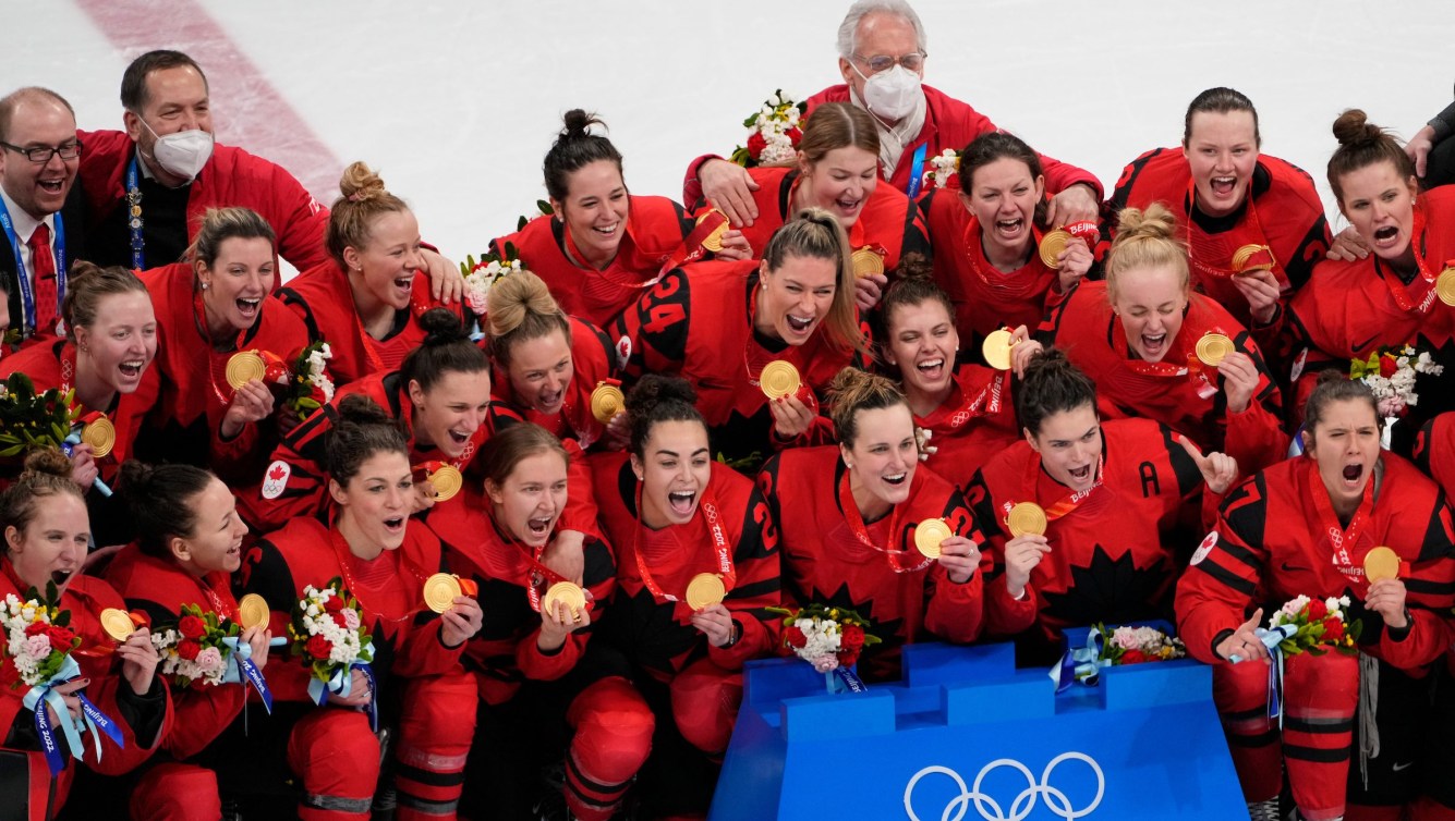 Team Canada grin and yell as they wear their gold medals on the ice