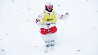 Mikael Kingsbury wears a yellow jersey as he skis down a moguls course