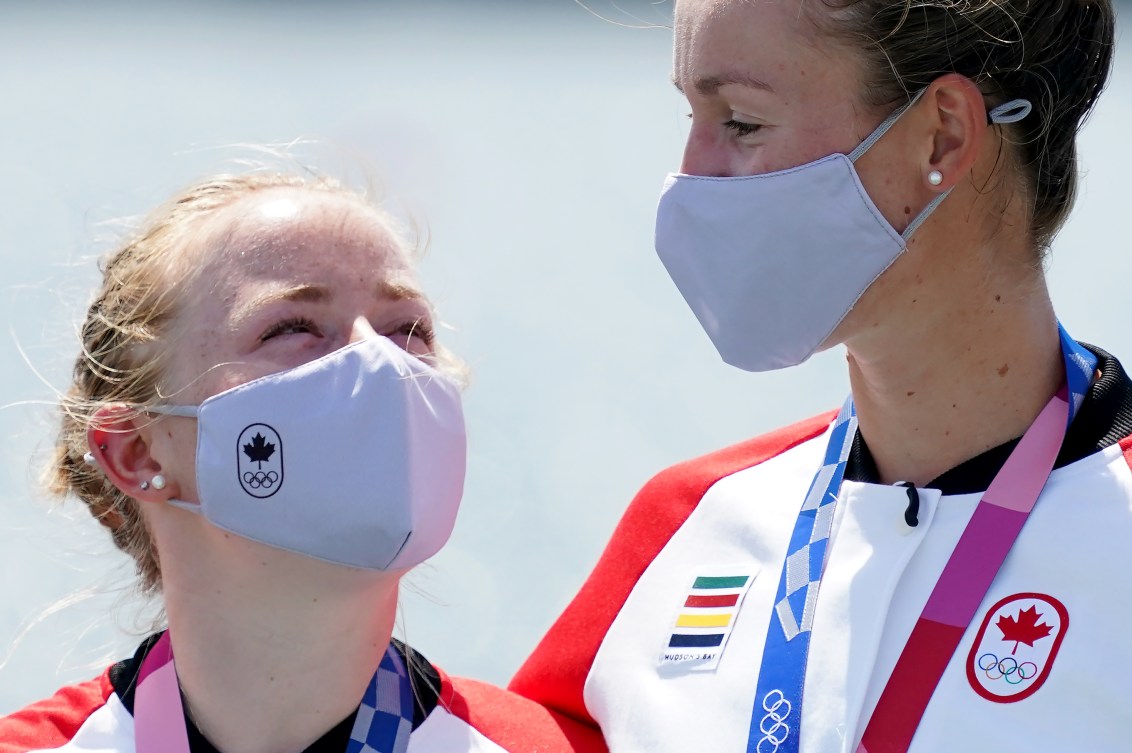 Caileigh Filmer and Hillary Janssens gaze at each other over their masks while wearing medals 