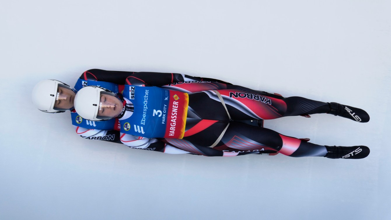 Two women slide on a doubles luge sled 