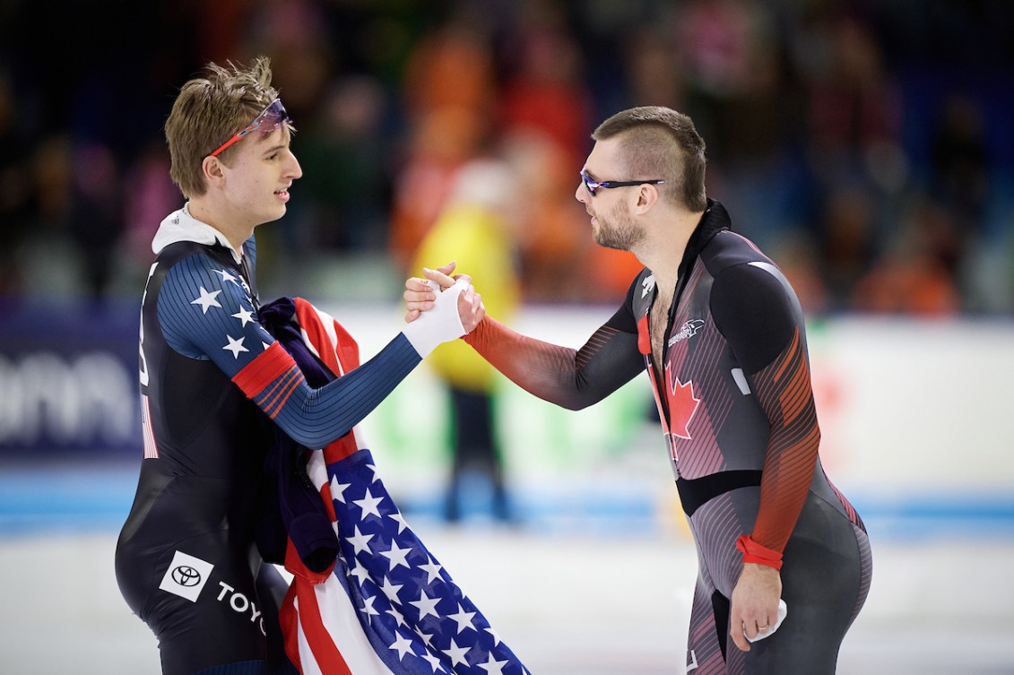 An American speed skater and a Canadian speed skater shake hands 