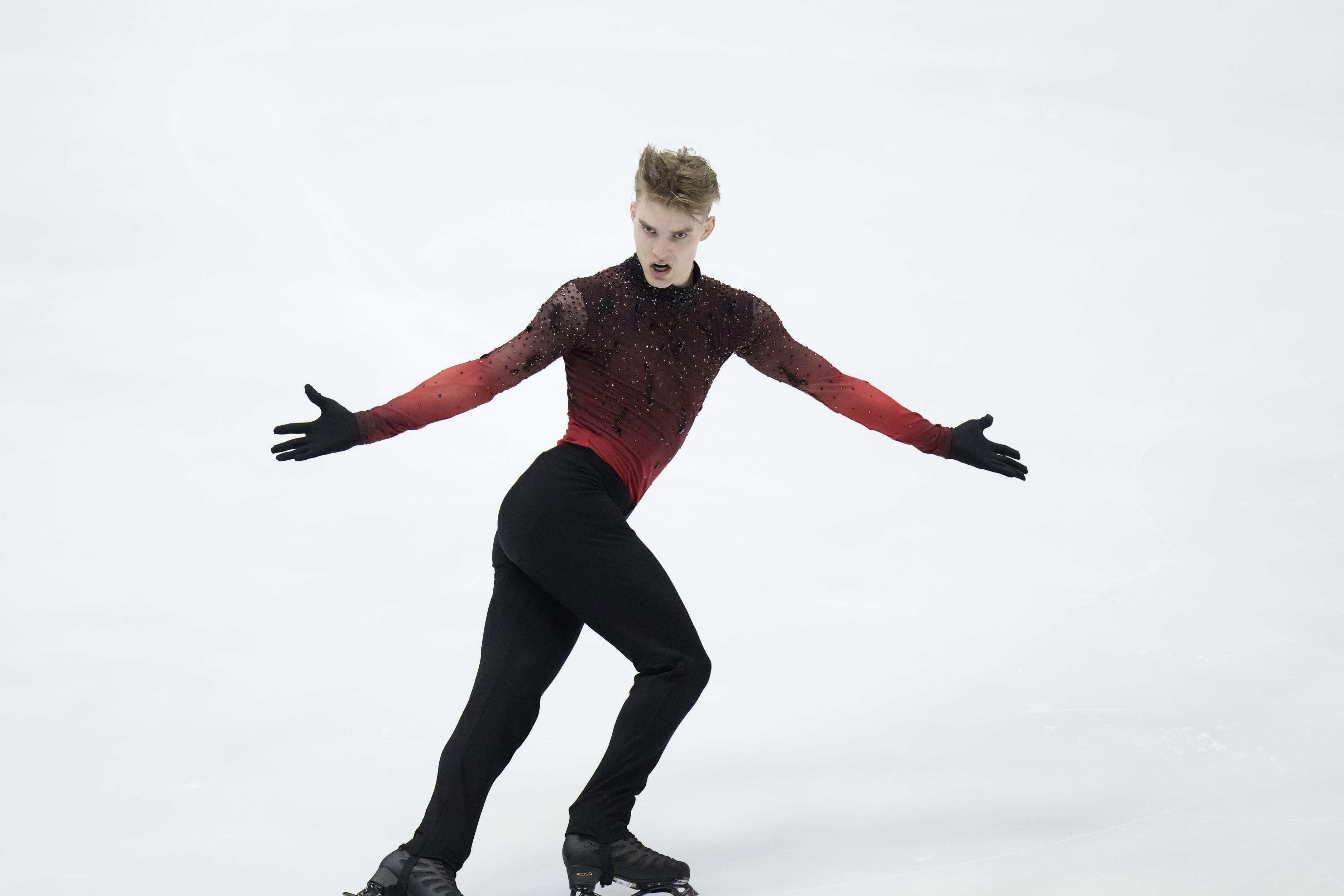 Conrad Orzel spreads his arms as he glides on the ice 