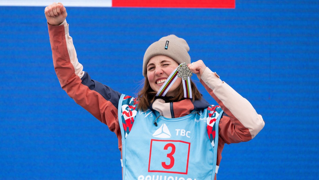 Elizabeth Hosking grins widely as she holds up her silver medal around her neck