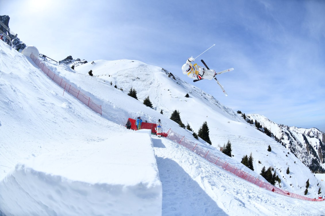 Side view of Mikael Kingsbury performing an aerial trick on a moguls course 