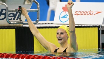 Summer McIntosh raises her arms in celebration while in the water by the side of the pool