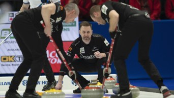 Canada skip Brad Gushue watches a shot approach the house as second EJ Harnden (left) and lead Geoff Walker sweep during second end action against Scotland in finals at the Men's World Curling Championship, in Ottawa, Sunday, April 9, 2023. THE CANADIAN PRESS/Adrian Wyld