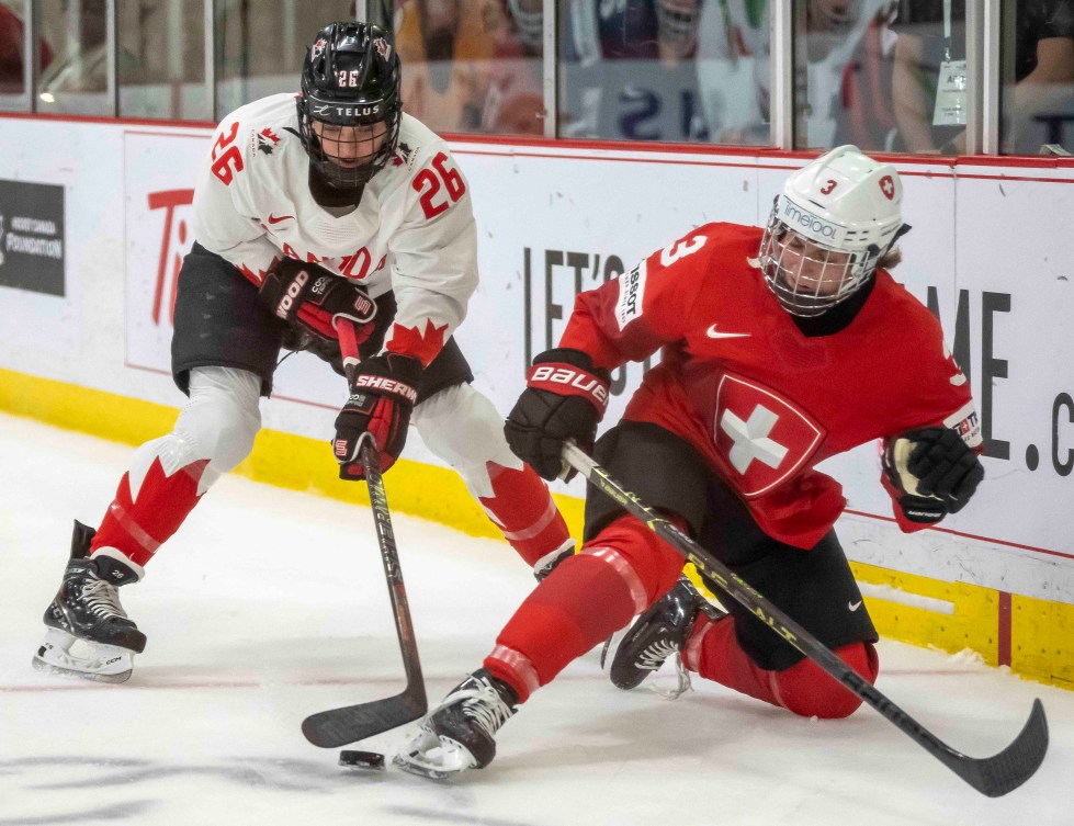 Team Canada's Emily Clark knocks Switzerland's Sarah Forster off the puck at the 2023 IIHF Women's World Championship.