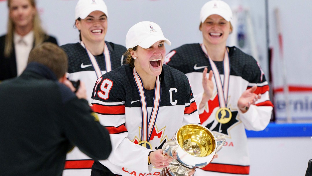 Marie-Philip Poulin holds the world championship trophy and wears a gold medal