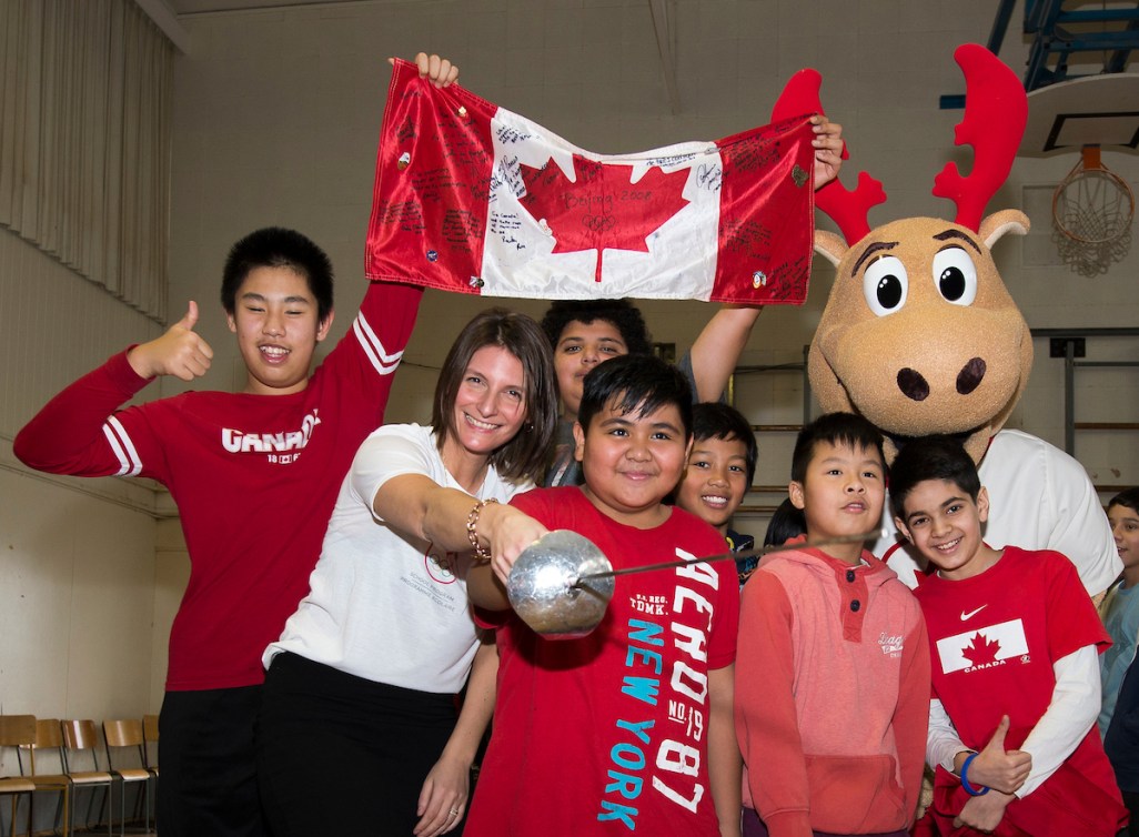 Fencer Sandra Sassine points her sword at the camera while surrounded by children