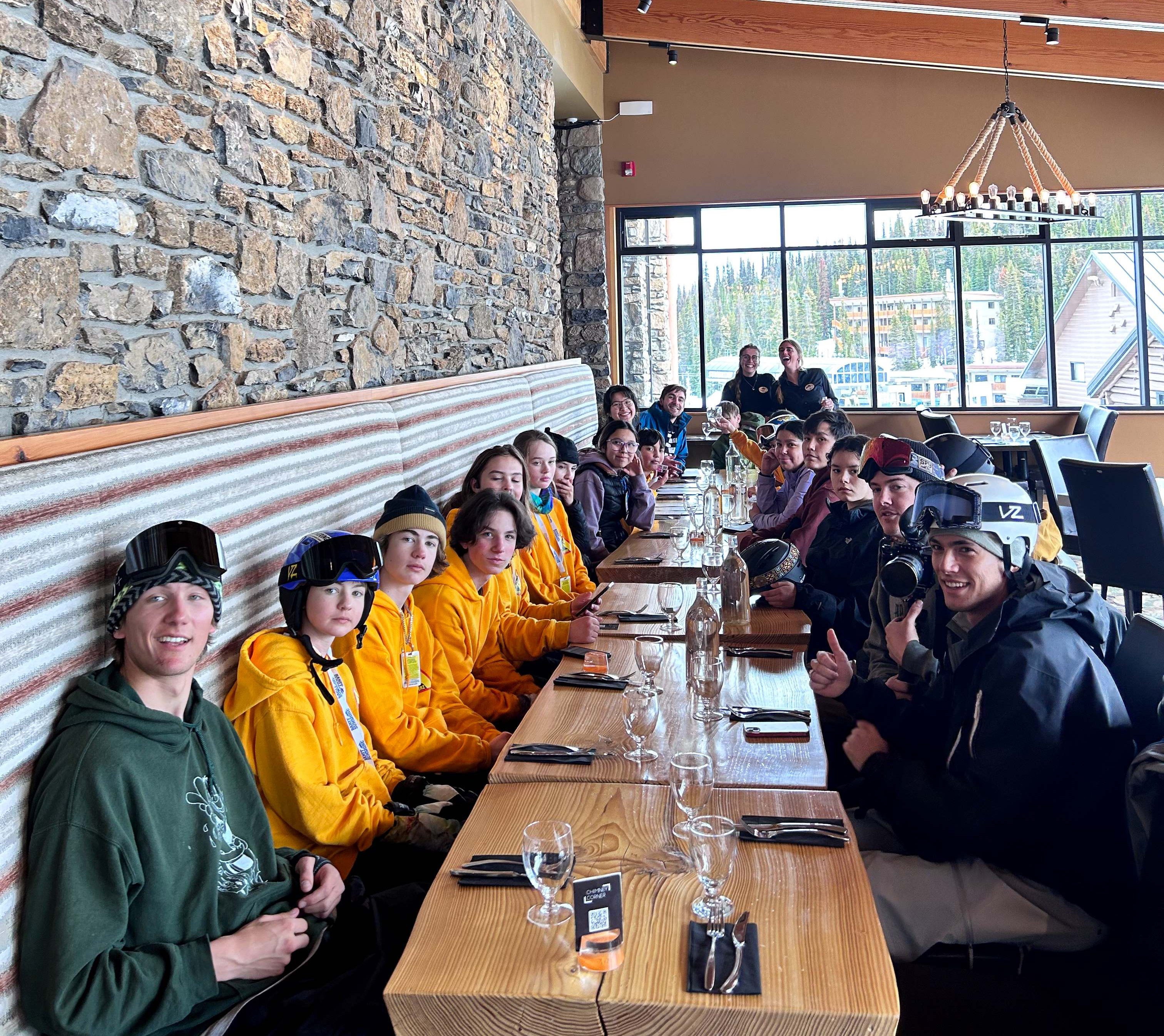 Liam Gill and a group of young Indigenous snowboarders eat at a long table in a restaurant