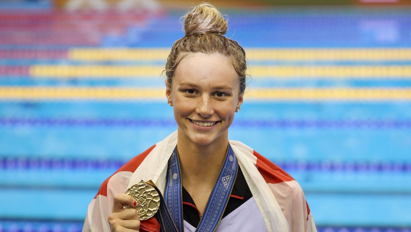 Summer McIntosh poses with her gold medal and a Canadian flag draped over her shoulder