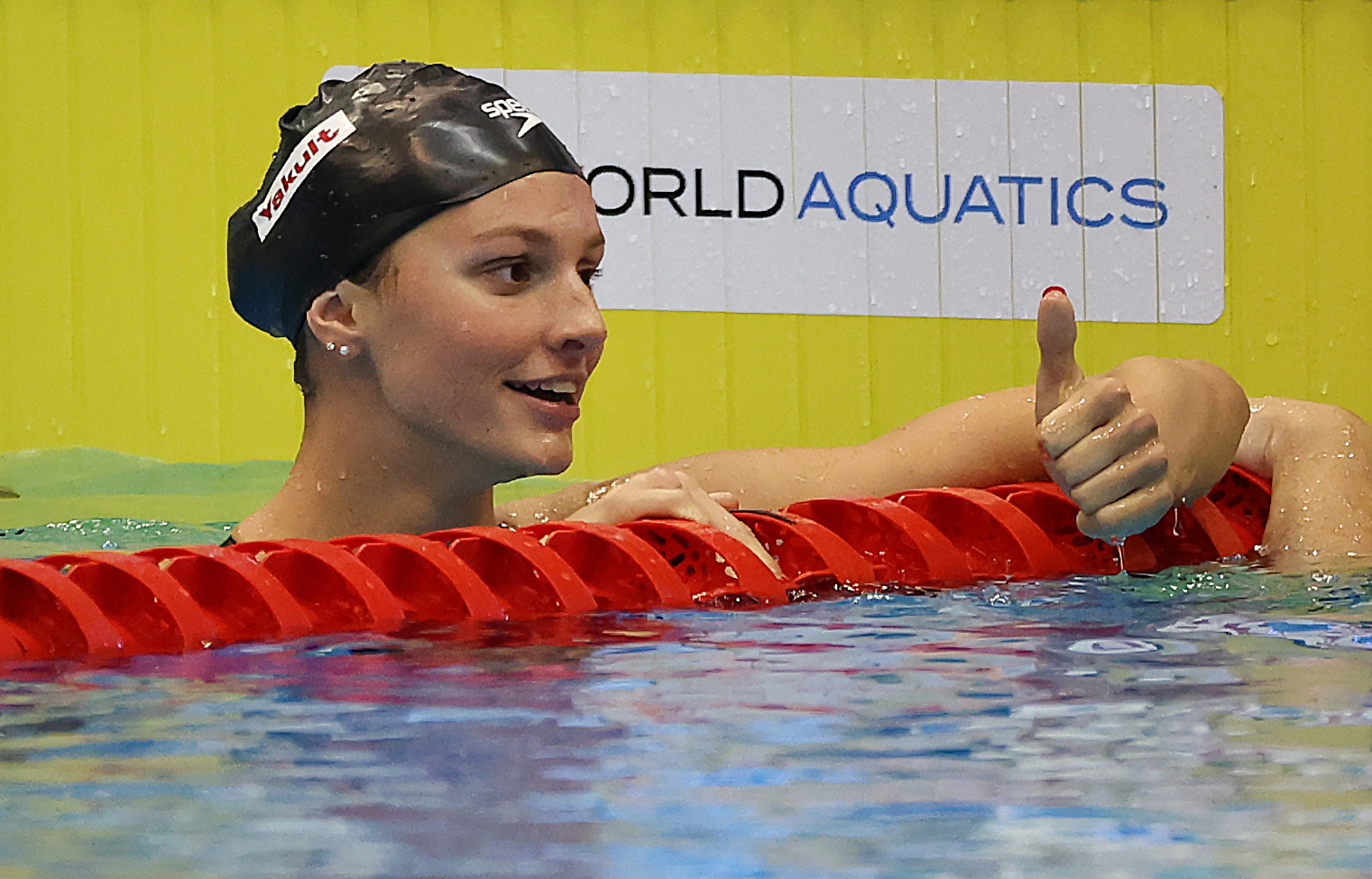 Summer McIntosh gives a thumbs up while hanging off the lane rope