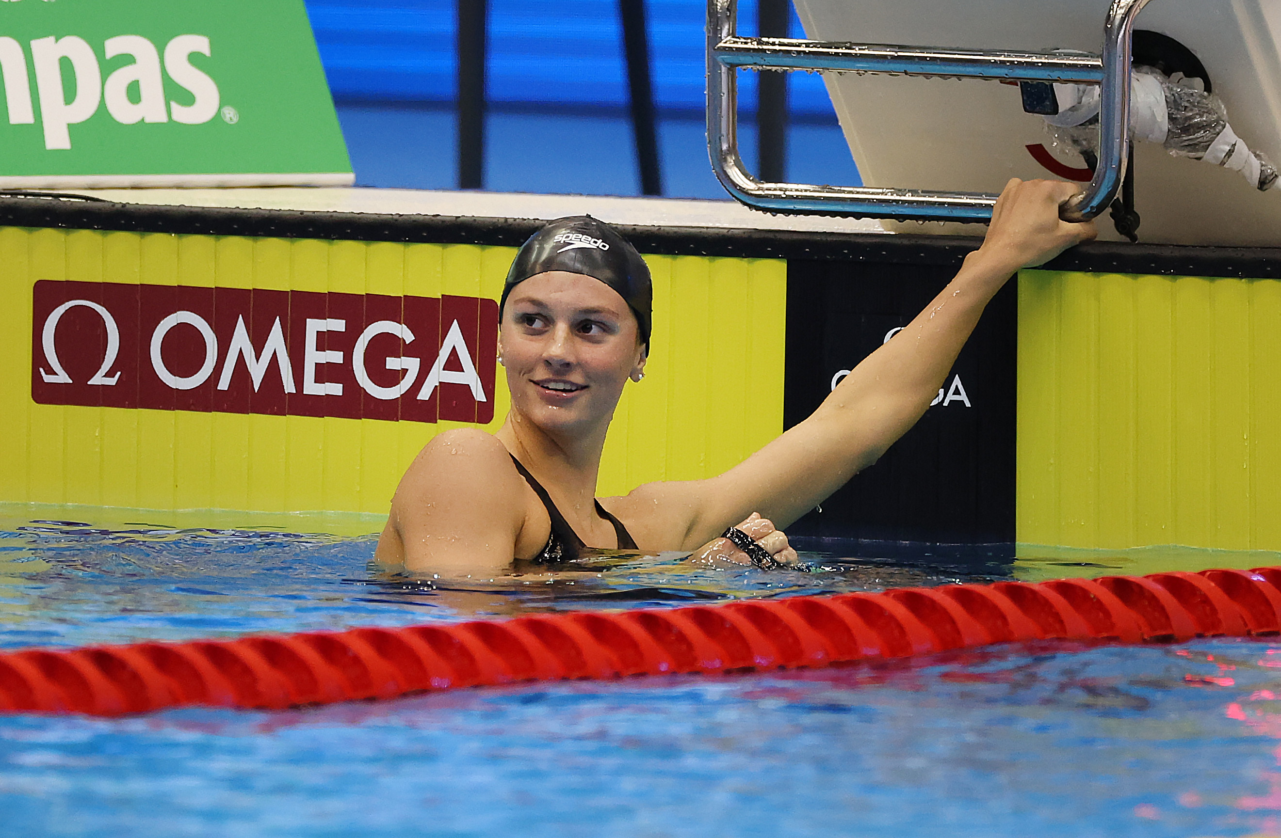 Summer McIntosh hangs off the wall of the pool as she looks at the scoreboard