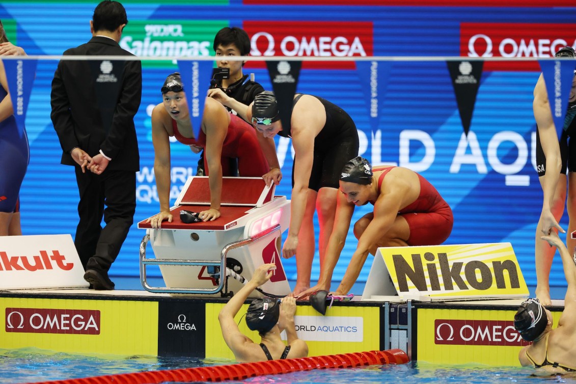 Canada's women's 4x100m medley relay team Kylie Masse, right, Sophie Angus, Maggie Mac Neil and Summer McIntosh in the water celebrate.