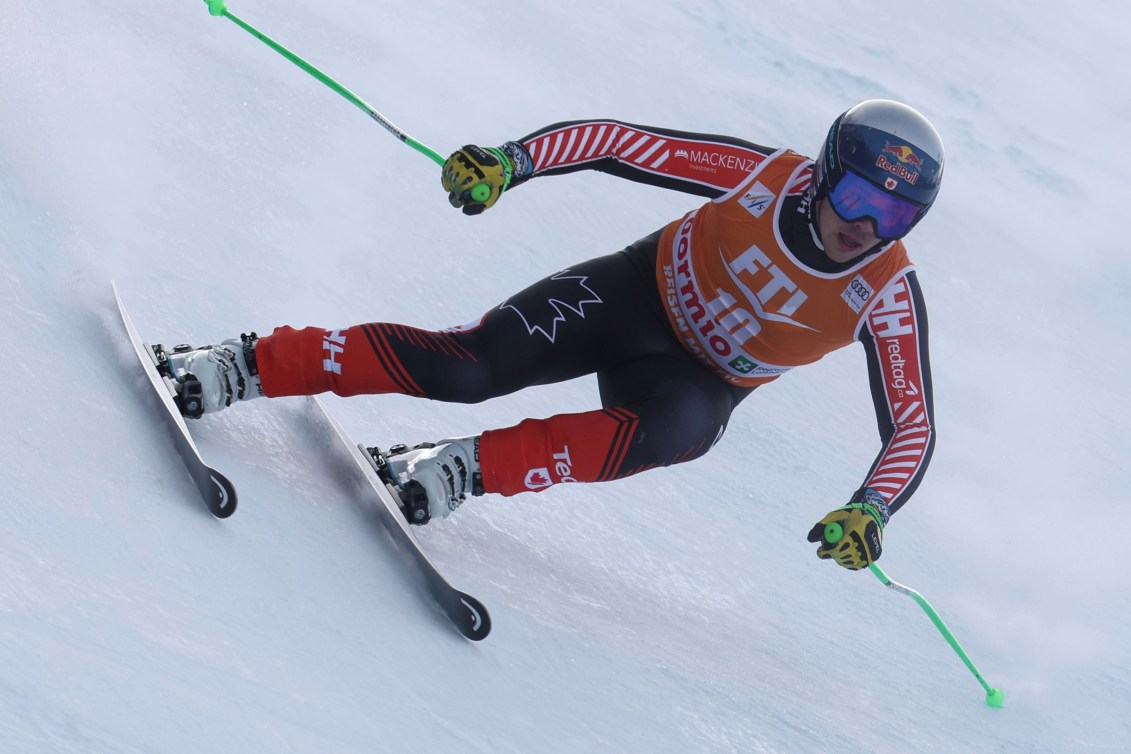 James Crawford leans while skiing, wearing an orange bib