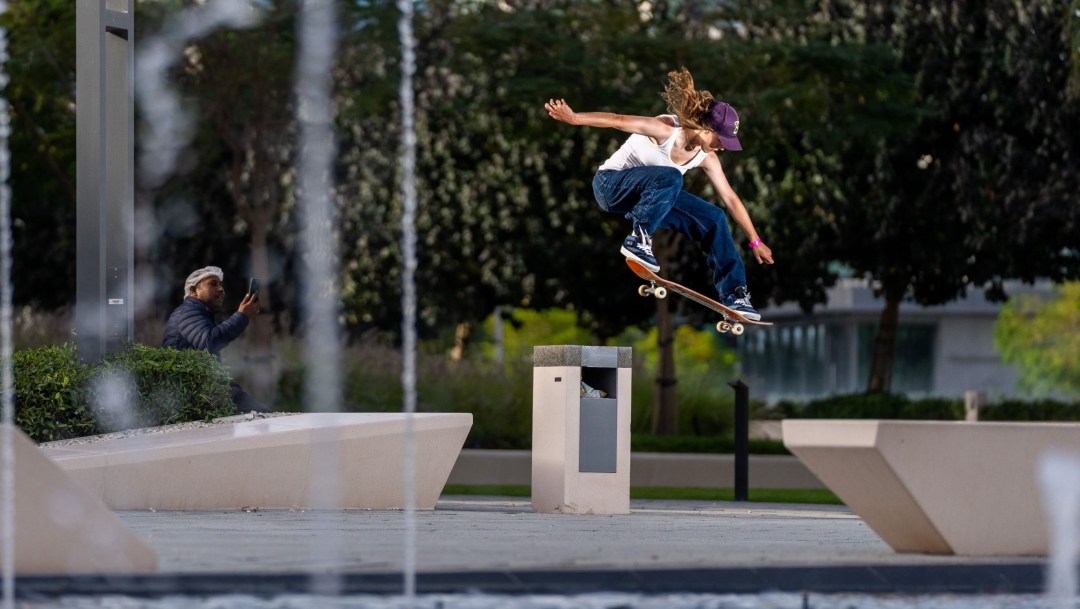 A female skateboarder skates over obstacles on a course