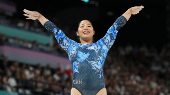 Cassie Lee smiles while raising her arms in the air