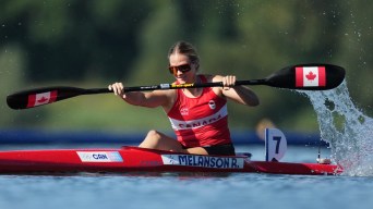 Riley Melanson races with paddles featuring Canadian flags