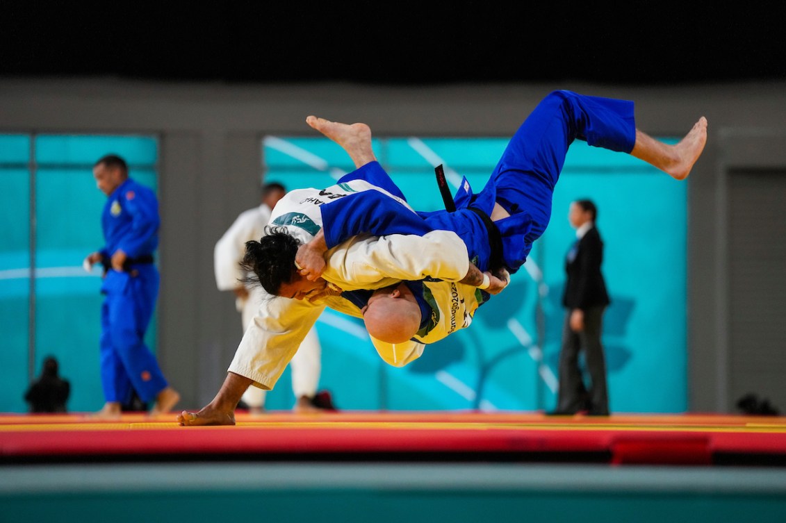 A judoka in white throws a judoka in blue to the mat