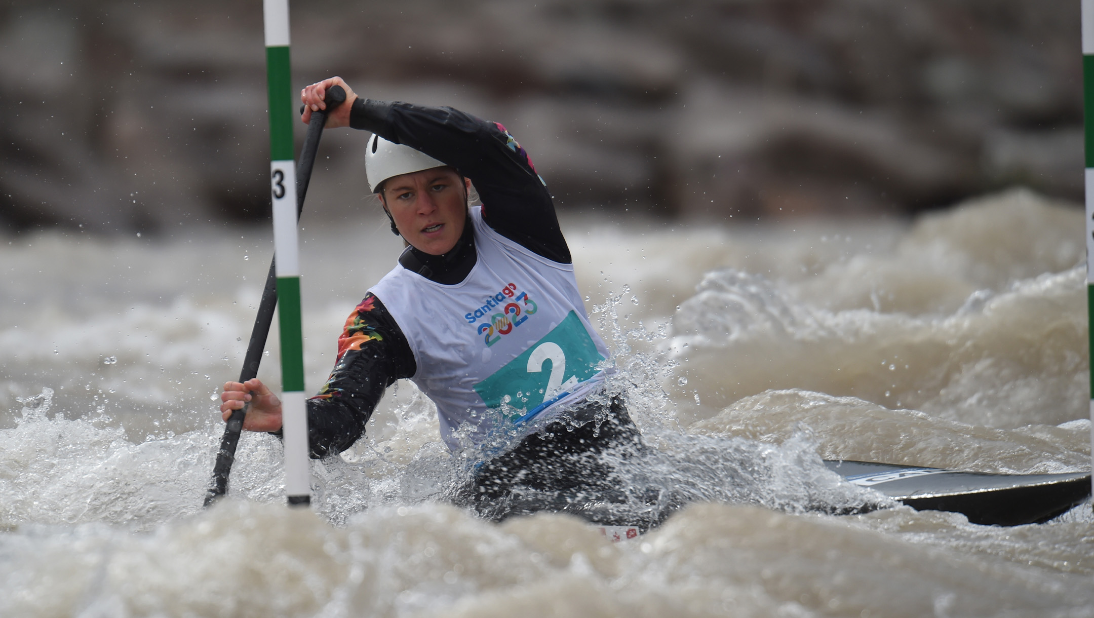 Lois Betteridge paddles her canoe past a green and white striped gate