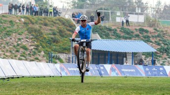 Gunnar Holmgren gives a fist pump and pops his front wheel as he crosses the finish line in first place