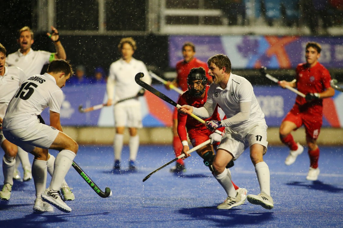 Multiple field hockey players fight for possession of the ball