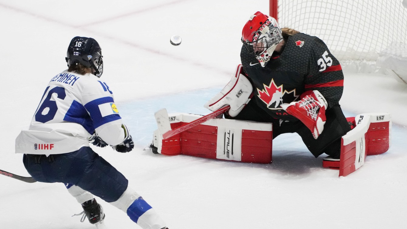 Team Canada goalie makes a save against a rushing Finnish player