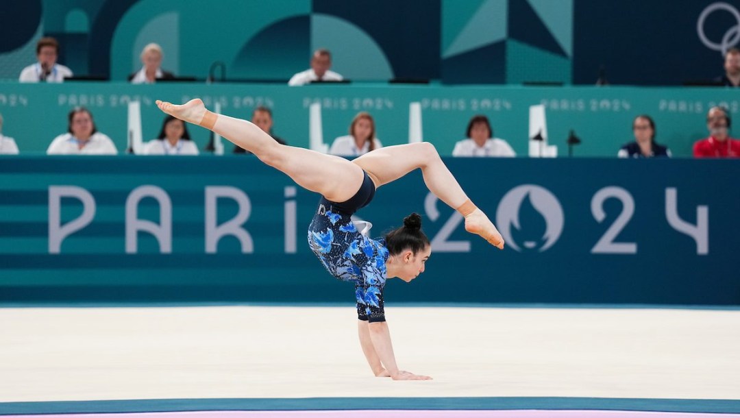 Ava Stewart does a split in the air while standing on her hands in a floor exercise routine