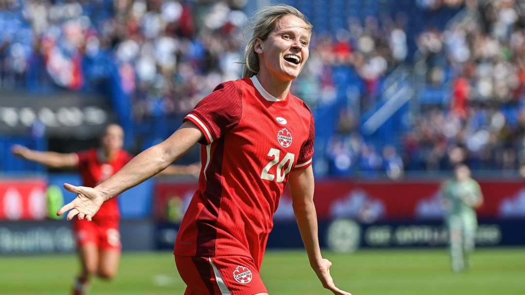 Cloé Lacasse in a red soccer uniform holds her hands out to celebrate scoring a goal