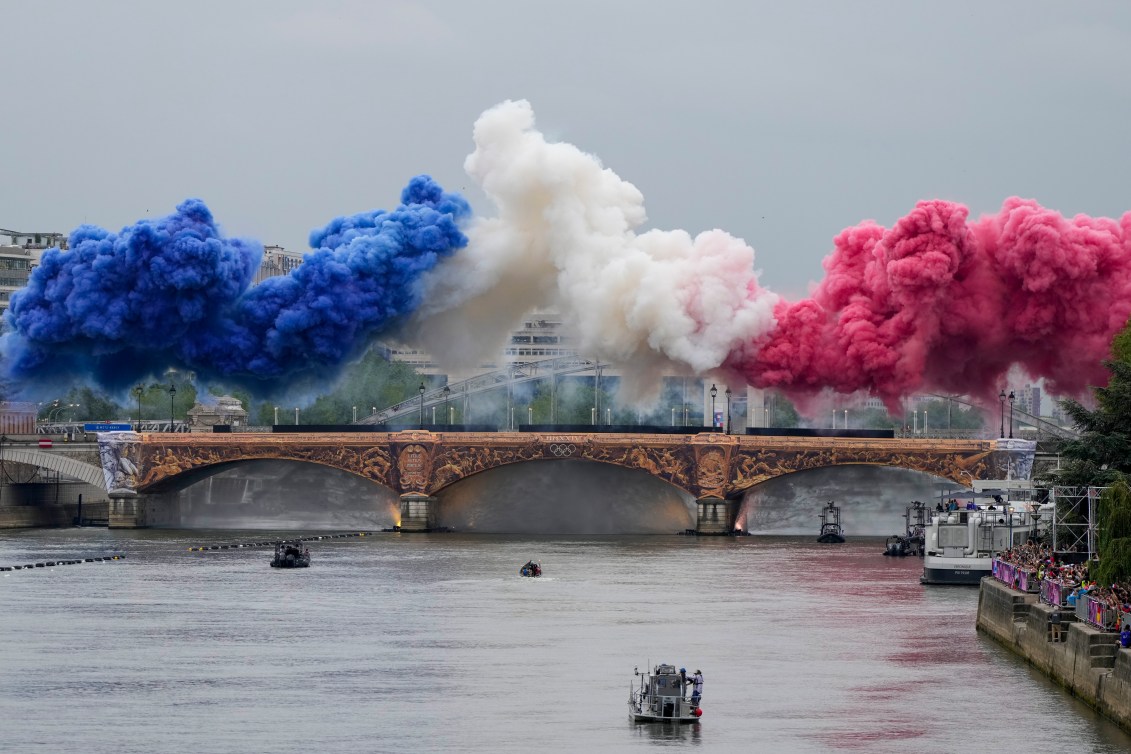 Ceremonial smoke in the colors of the France flag appear over the Seine River in Paris, France, during the opening ceremony of Paris 2024.