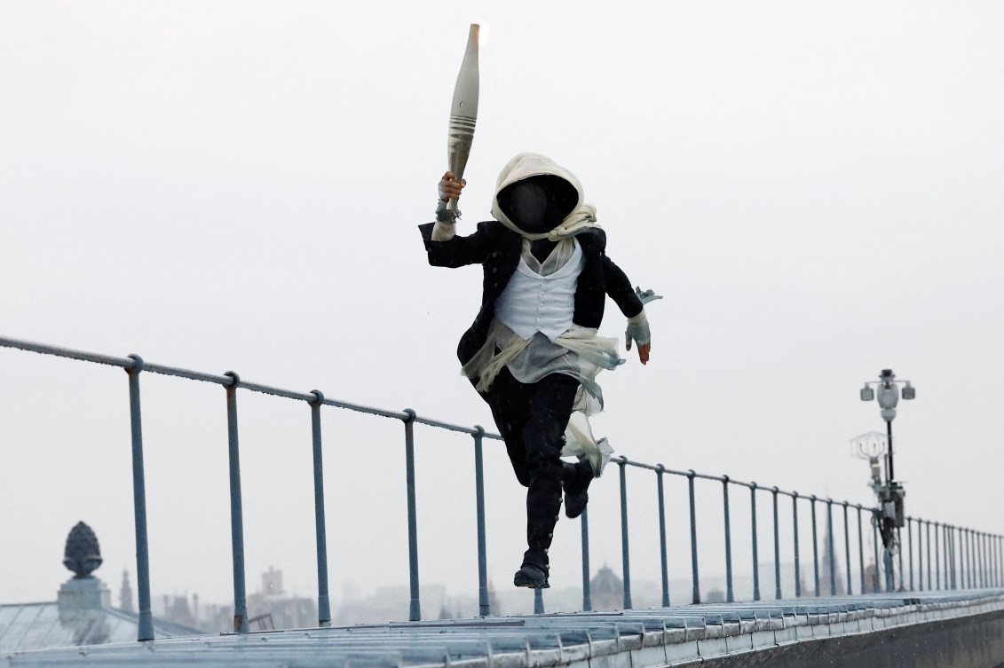 A masked torch bearer runs in Paris 