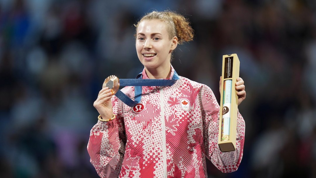 Eleanor Harvey poses with her medal and a box containing a poster on the podium