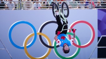 Jeff Whaley flips upside down on his bike in front of the Olympic rings