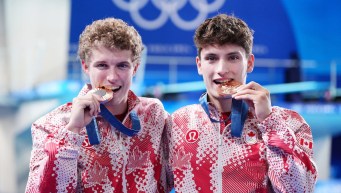 Rylan Wiens and Nathan Zsombor-Murray bite their bronze medals