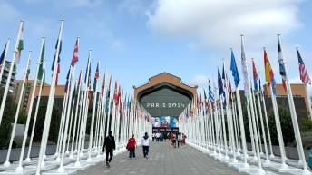 the walkway up to the main building at the Paris 2024 Olympic Village is lined with the flags of competing nations