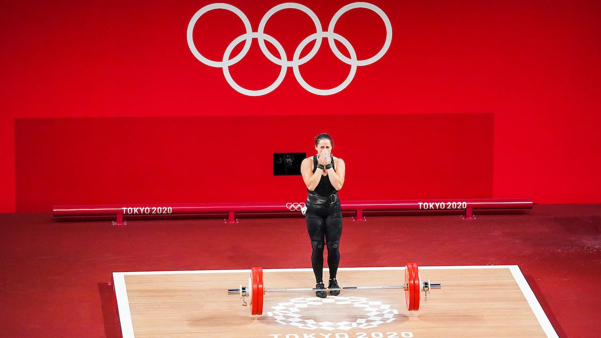 Maude Charron stands on the weightlifting platform with her hands over her mouth