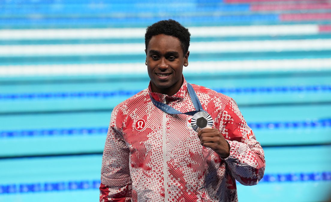 Josh Liendo poses with his silver medal in a red and white track suit 