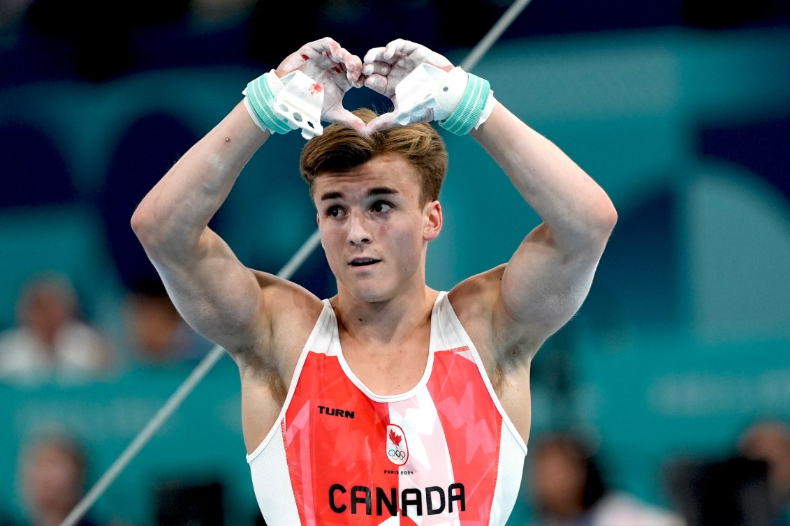 Felix Dolci reacts with a hand heart after his fall off the high bar.