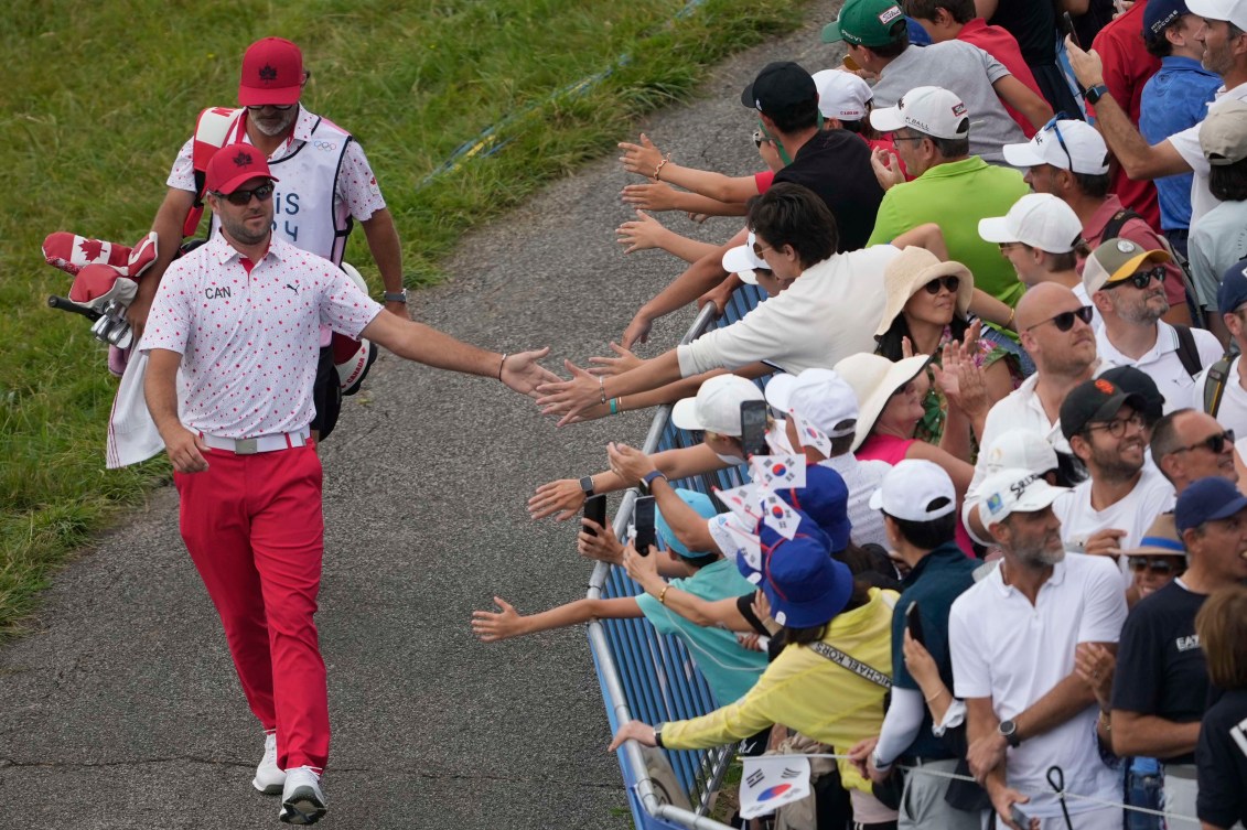 Corey Conners taps fans hands as he walks to the 1st tee