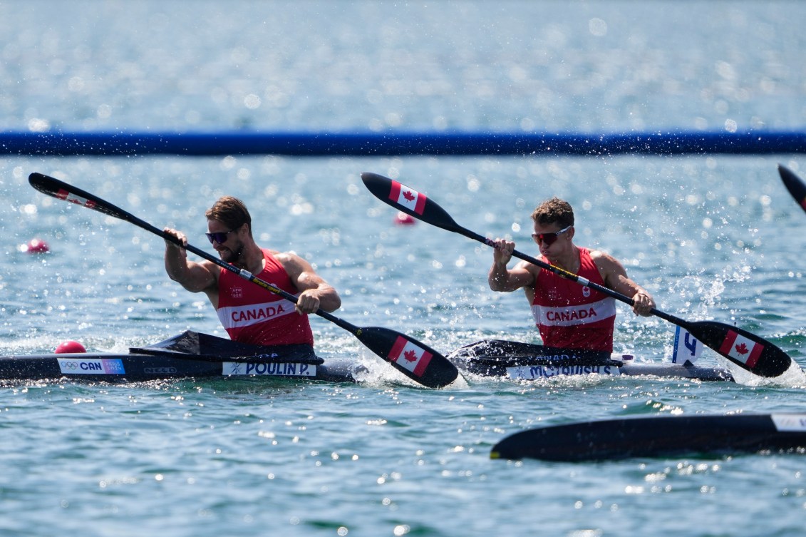 Two kayakers paddle in sync