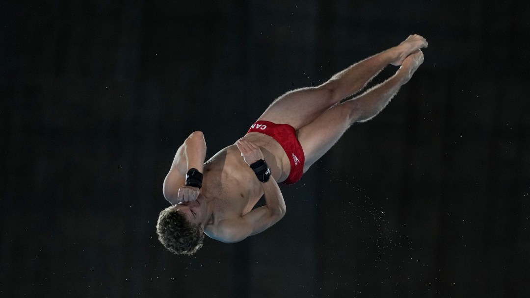 Rylan Wiens dives in a red swim trunks against a black background