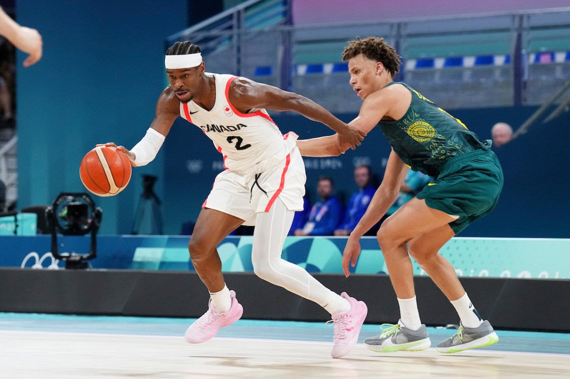 Shai Gilgeous-Alexander fends off an opponent while dribbling a basketball