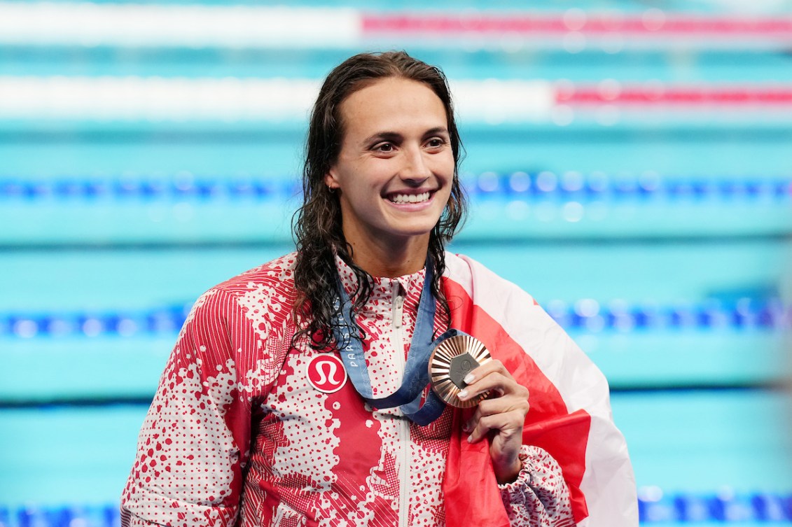 Kylie Masse wears a silver medal with her red and white track suit 