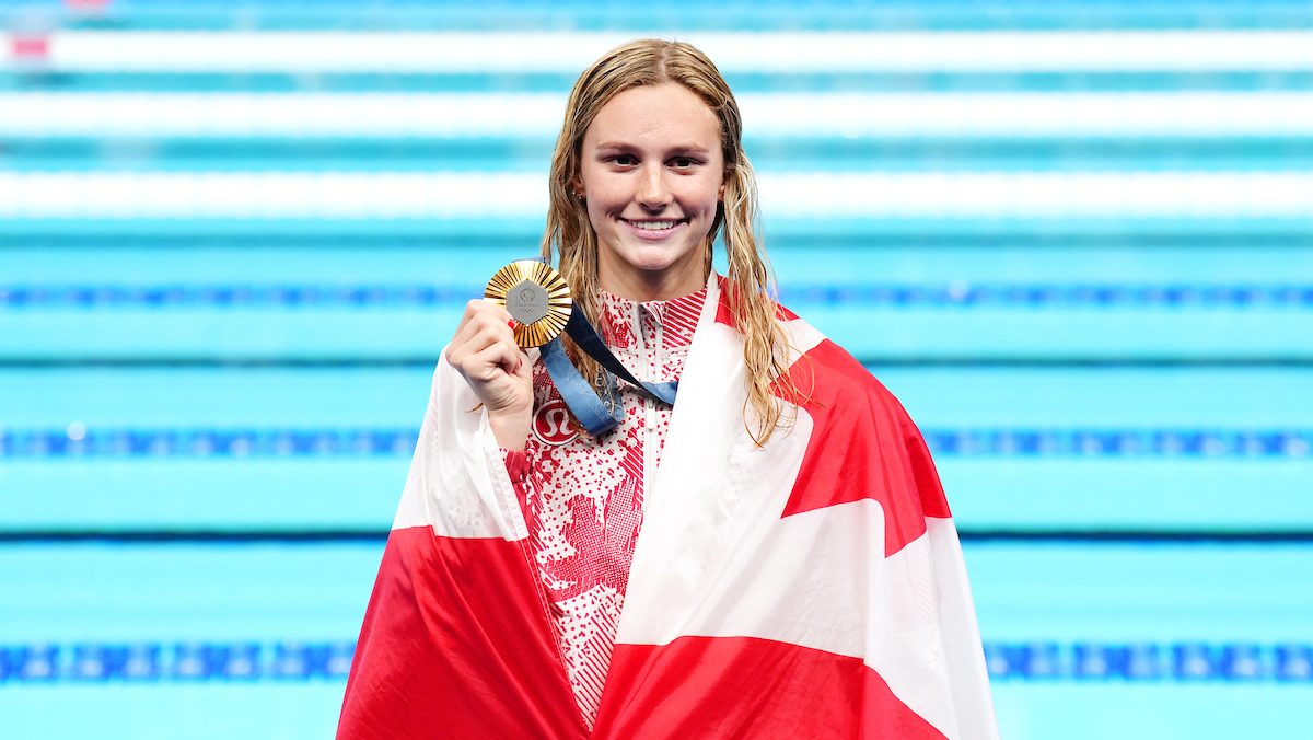 Summer McIntosh with her gold medal and a Canadian flag around her