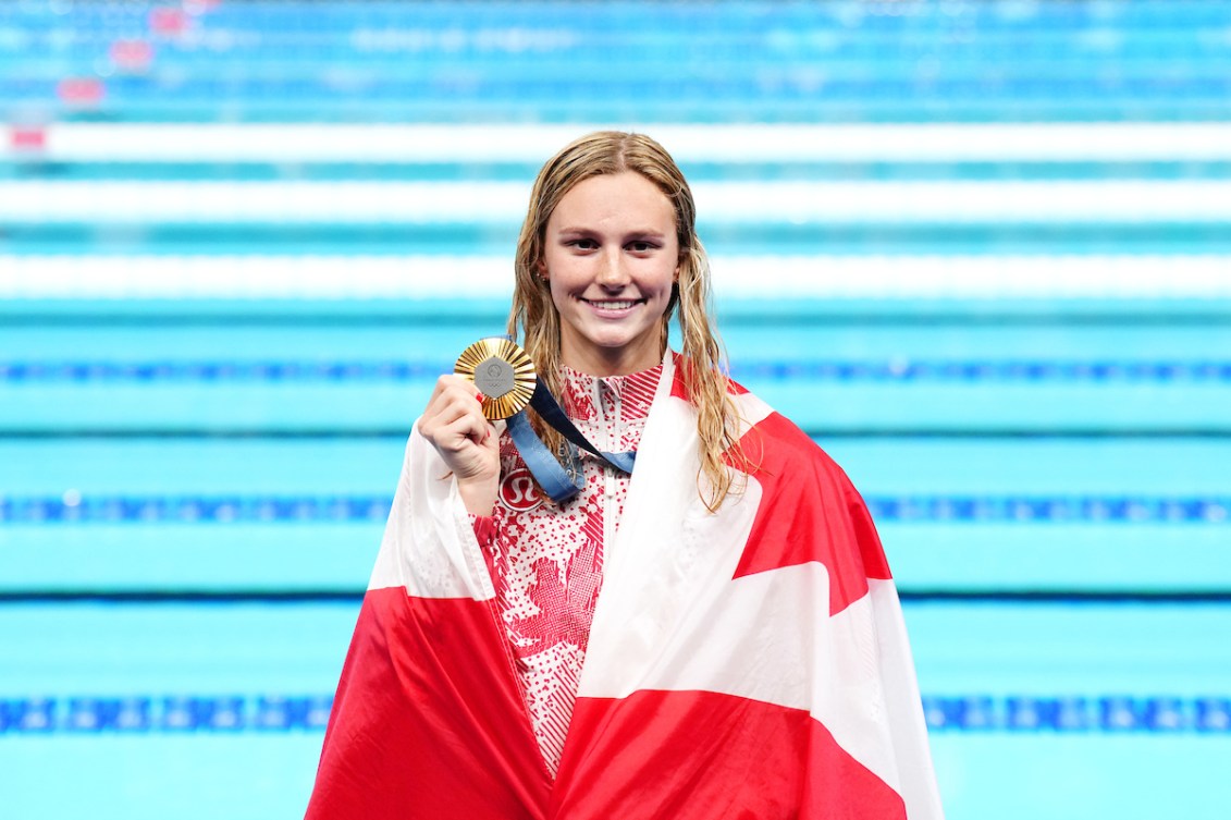 Summer McIntosh with her gold medal and a Canadian flag around her